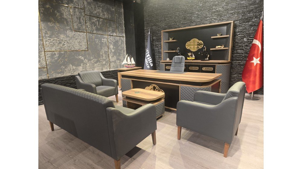 Kemer lüks yönetici masa takımı, gri kapitoneli panelleri, parlak altın rengi lazer kesim metal motifleri ve ceviz rengi tablası ile modern ofis ortamında sergileniyor.